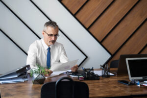 Empresário no escritório realizando consulta de CNPJ em papéis.